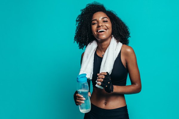 woman smiling after workout in front of a teal background