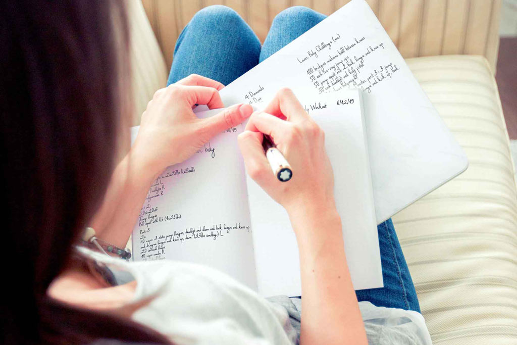 woman writing workout structure in workout journal