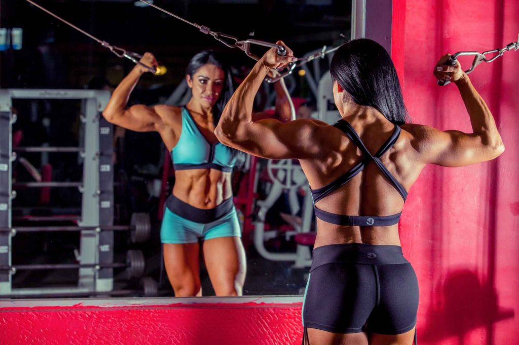 woman doing strength training with pulleys in mirror