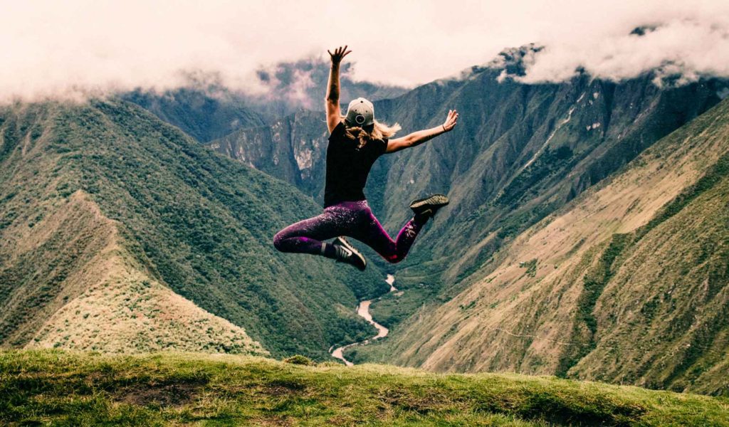 woman jumping for joy on mountaintop