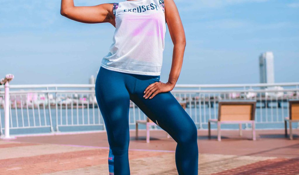 woman showing muscles after exercising on pier in city