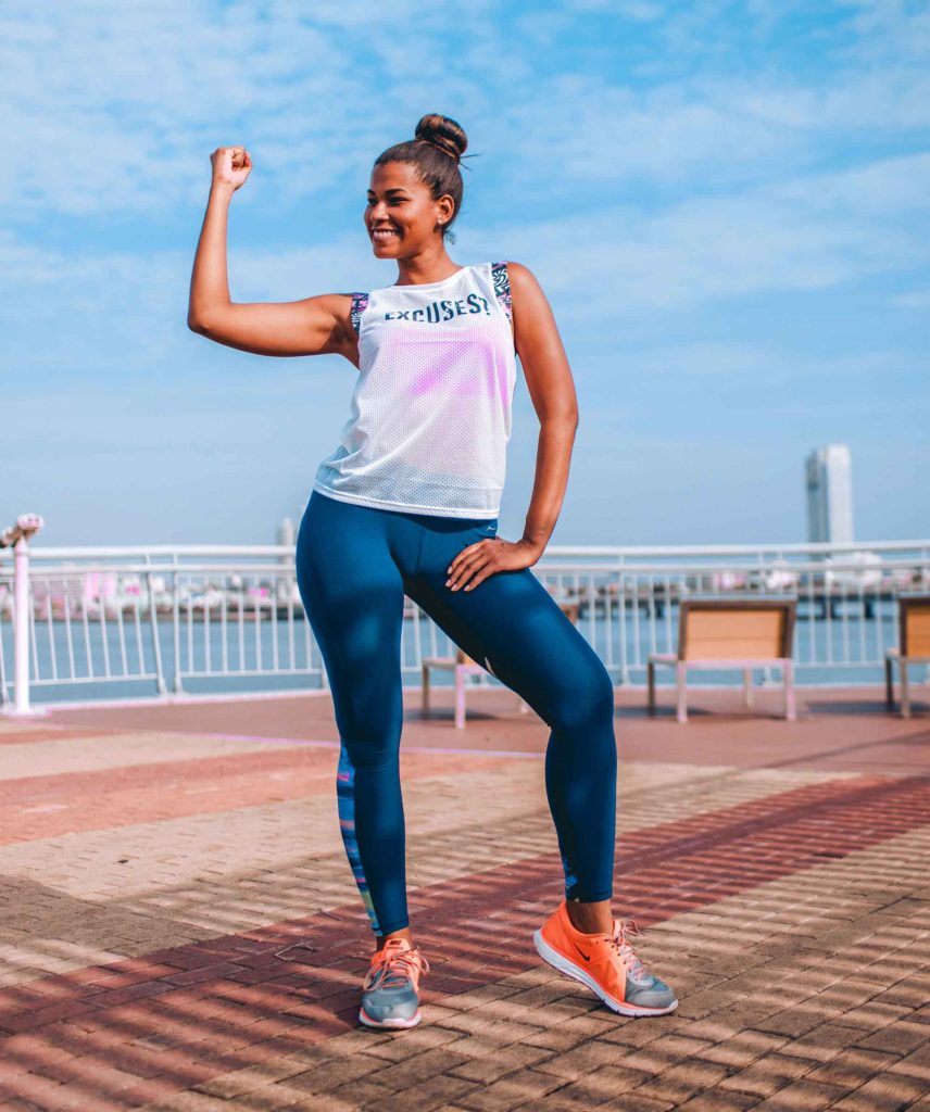 woman showing muscles after exercising on pier in city