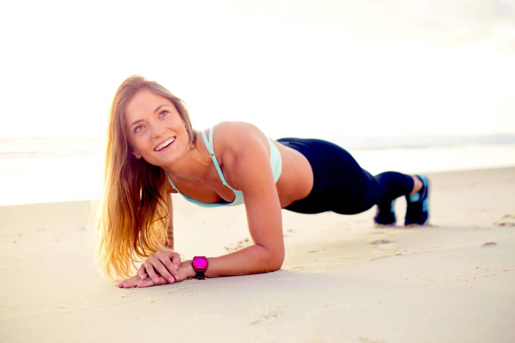 woman doing plank on beach and smiling