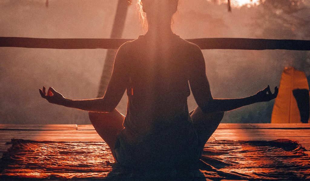 Woman meditating on deck at sunset
