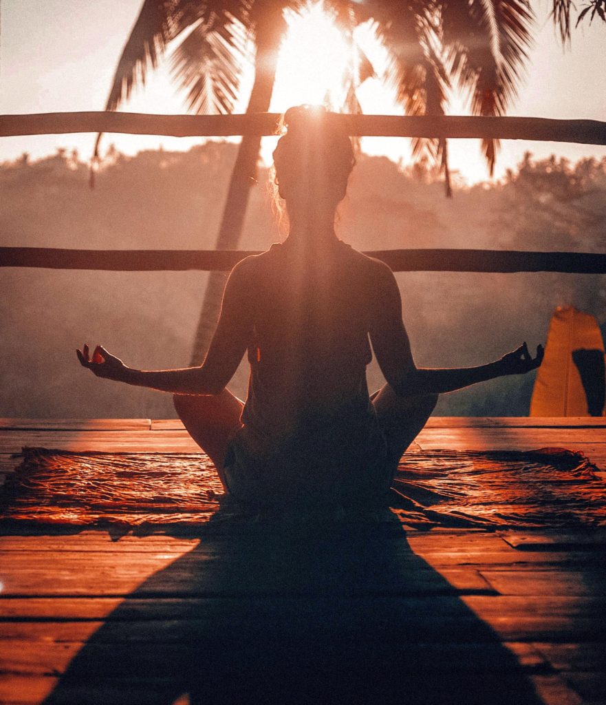 Woman meditating on deck at sunset