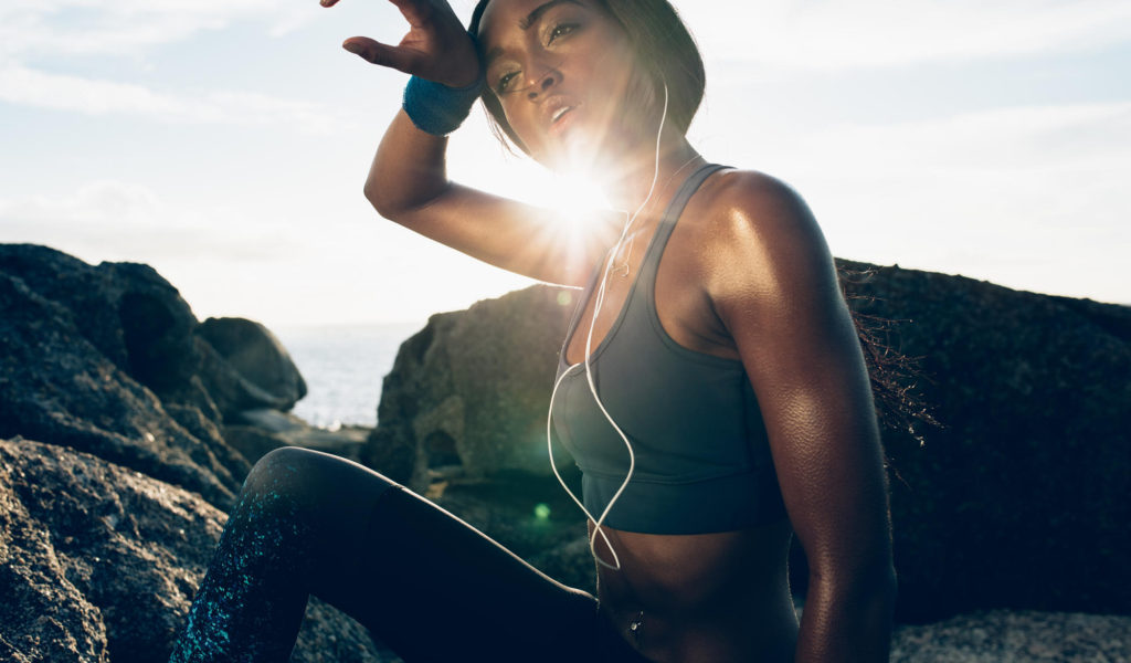 woman wiping herself off after intense workout outside