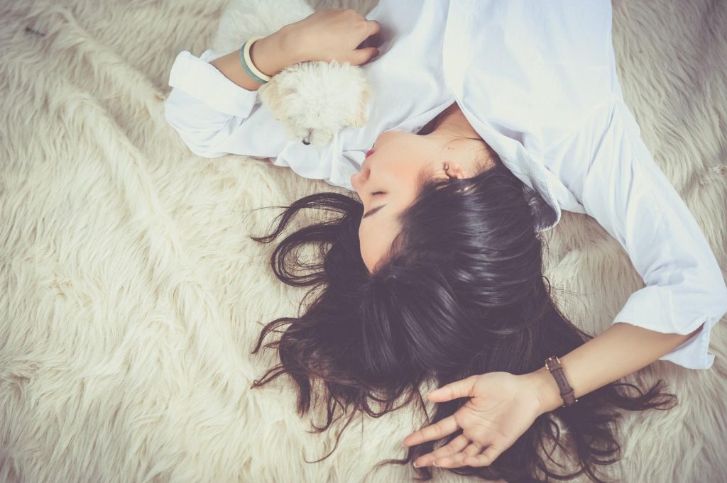 woman asleep on white fur with white dog