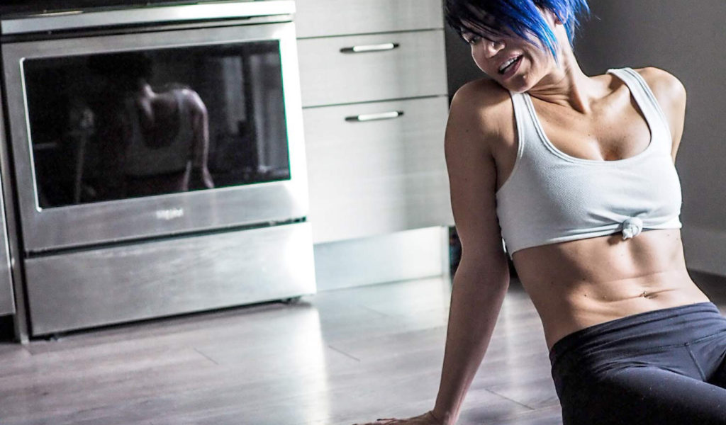 woman with blue hair on kitchen floor with dog after home workout