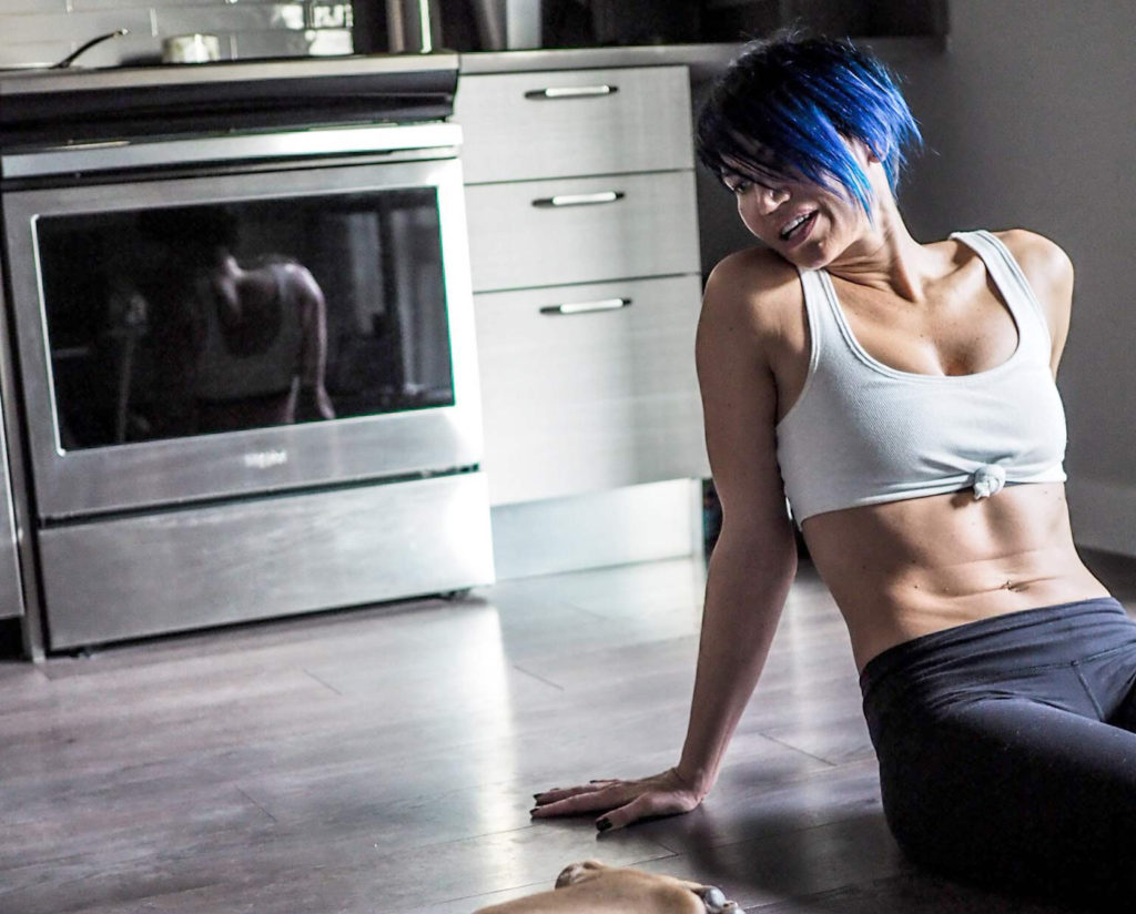 woman with blue hair on kitchen floor with dog after home workout