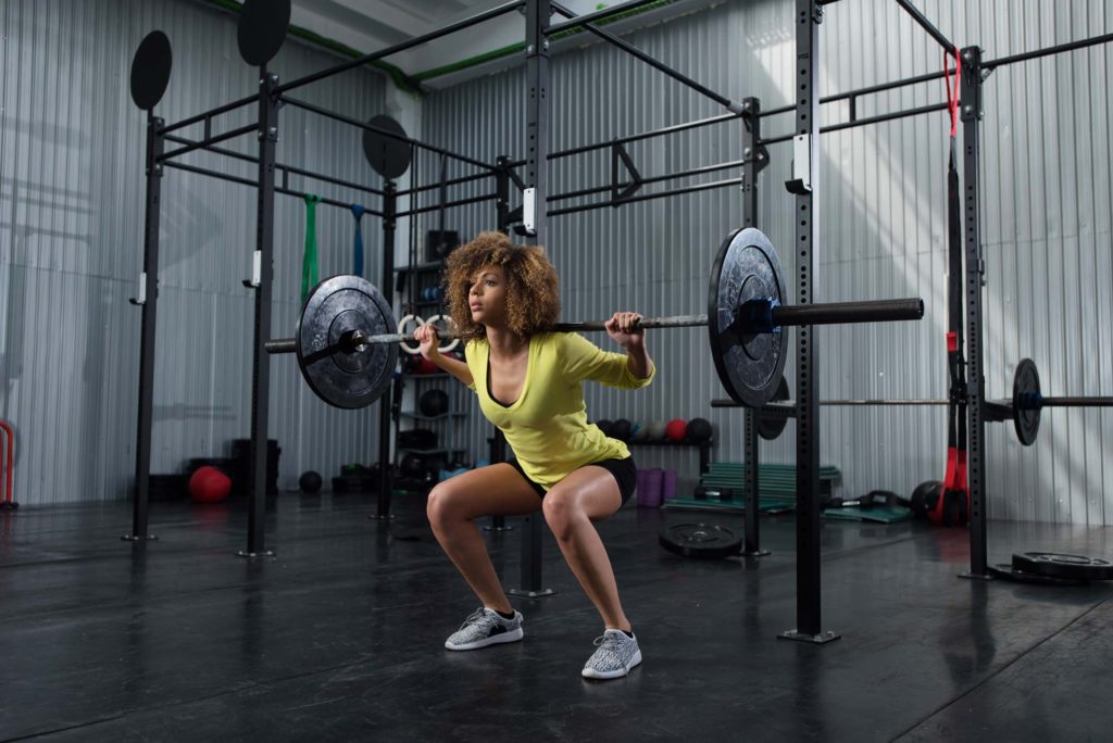 woman doing squats with barbell