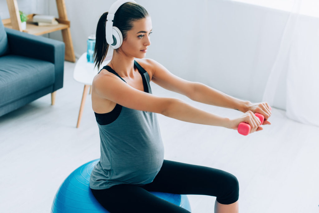 woman working out with dumbbells while pregnant