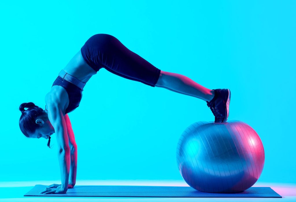 woman doing balance ball shoulder presses for calisthenics arm workout