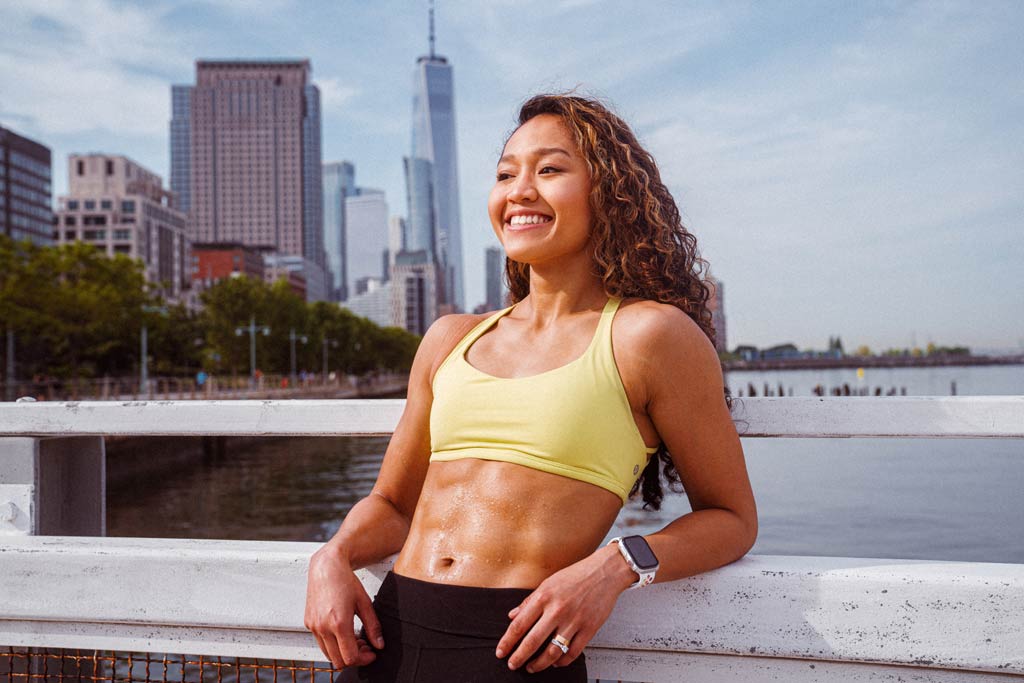 fit woman with 6 pack after hard workout of bodyweight supersets with manhattan in background