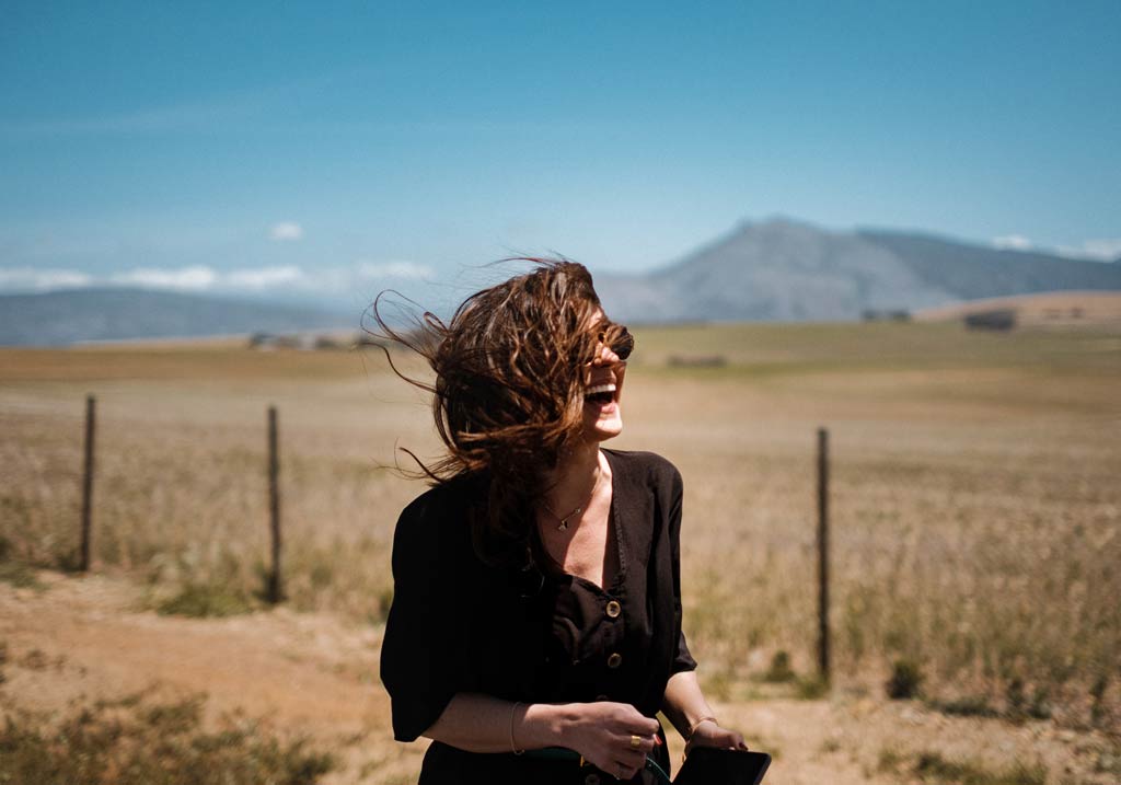 woman in sunglasses laughing in front of a field