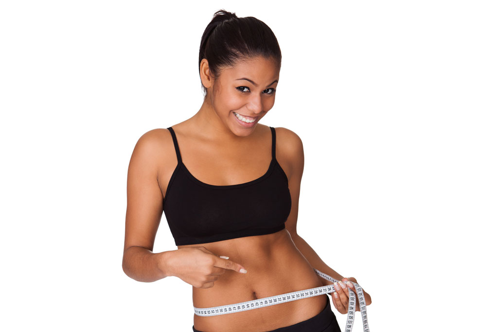 woman smiling and measuring her waist to see how much weight she has lost