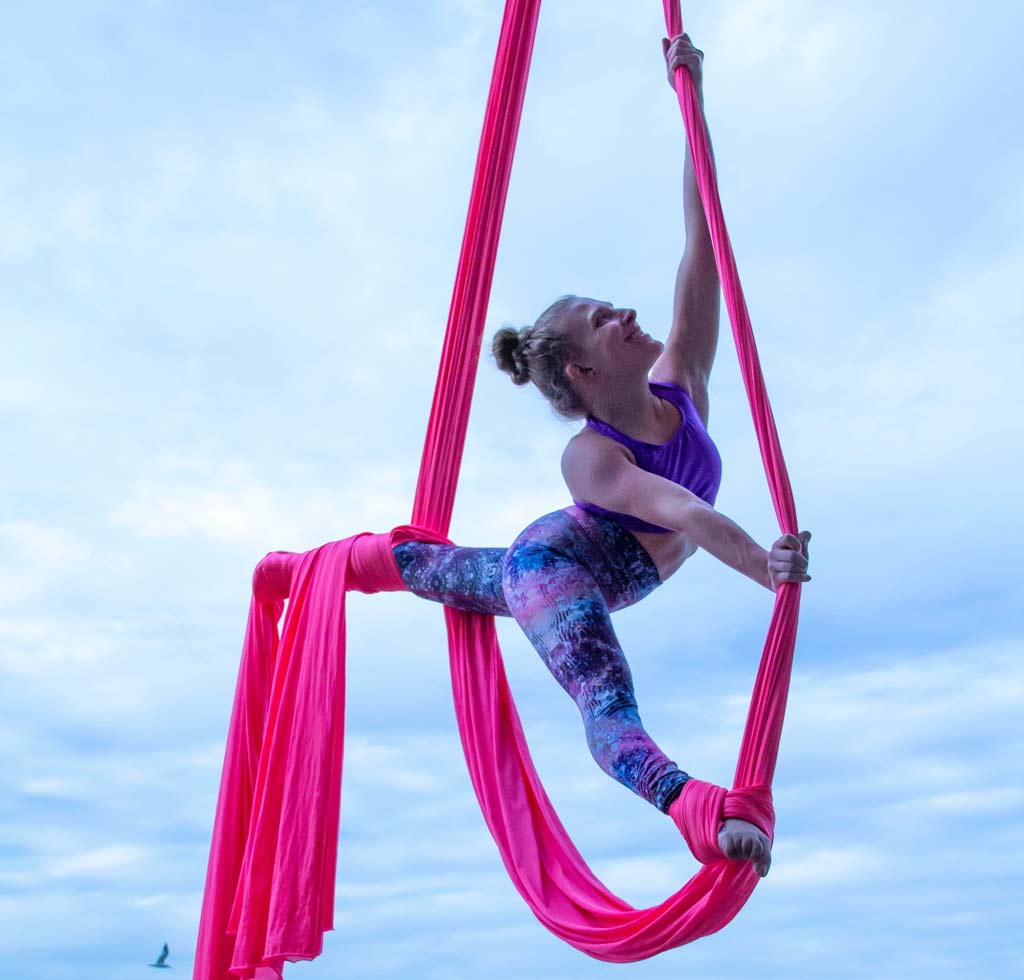 woman doing aerial silk with sky in background