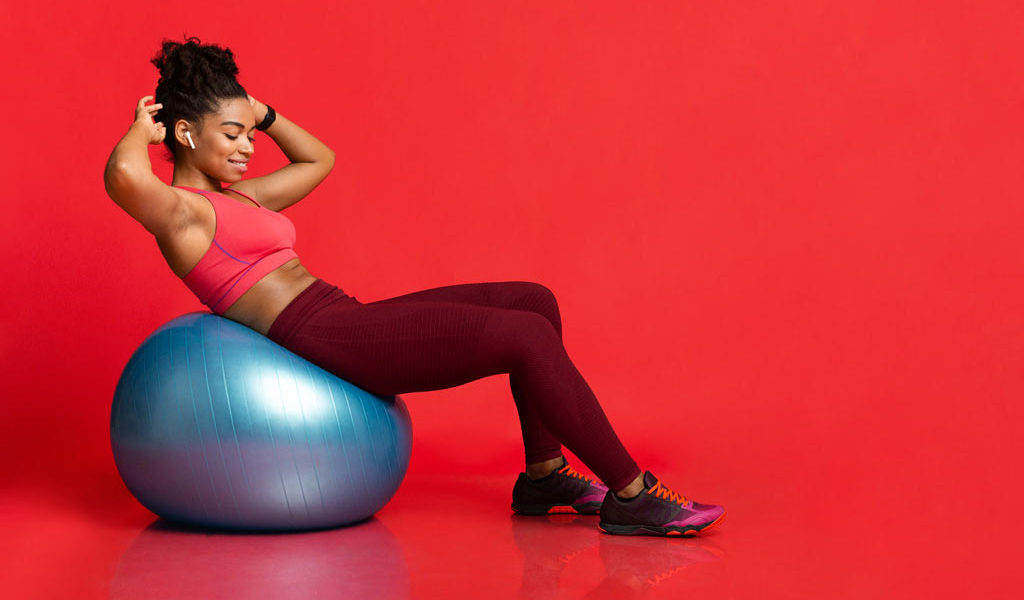 woman smiling getting fit doing crunches on beginners stability ball