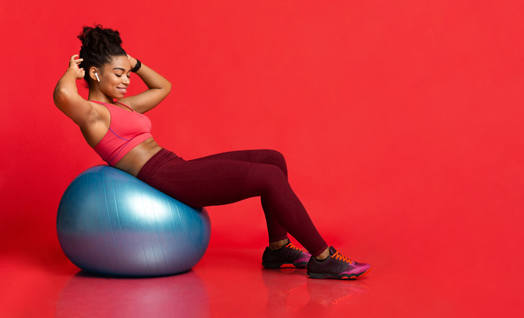 woman smiling getting fit doing crunches on beginners stability ball