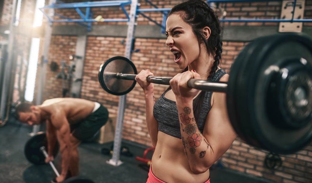 woman using progressive overload with barbell curls at gym