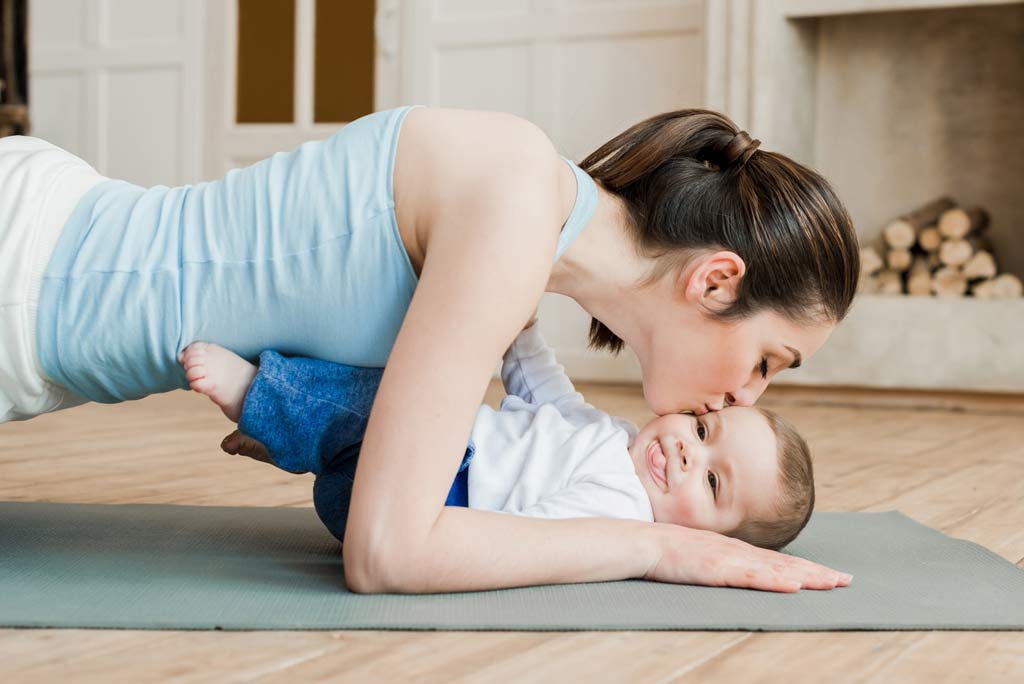 fit mom lying down kissing baby after workout