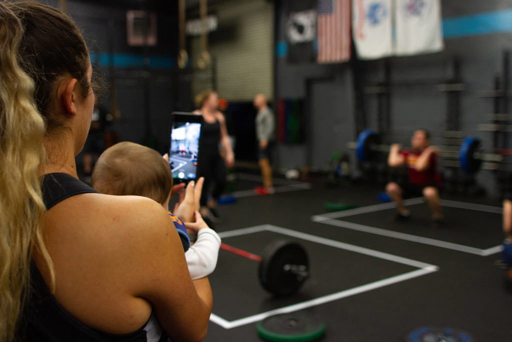 mom at gym with  baby making fitness video with phone