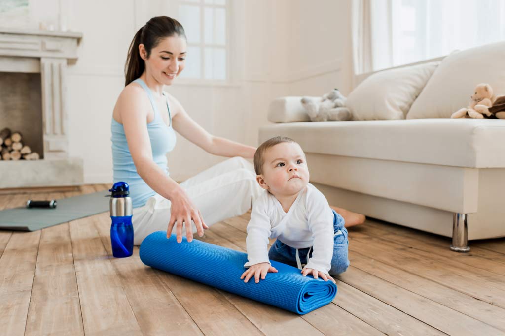 mom after workout with baby next to her workout mat
