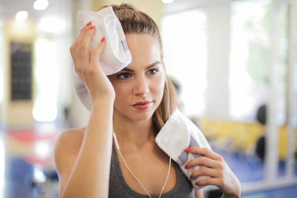 woman wiping forehead after hard hiit workout